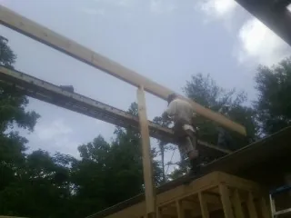Carpenter setting a ridge beam over a new addition frame — Ice Dam Removal by Roofing Brothers in Buna