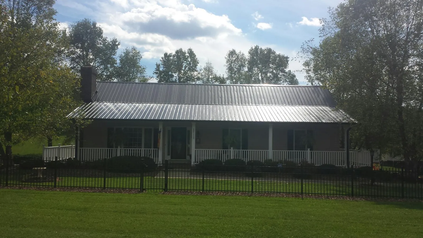 Gray metal roof on a brick ranch with a full width front porch — Gutter Guard Installation work by our crew in Buna