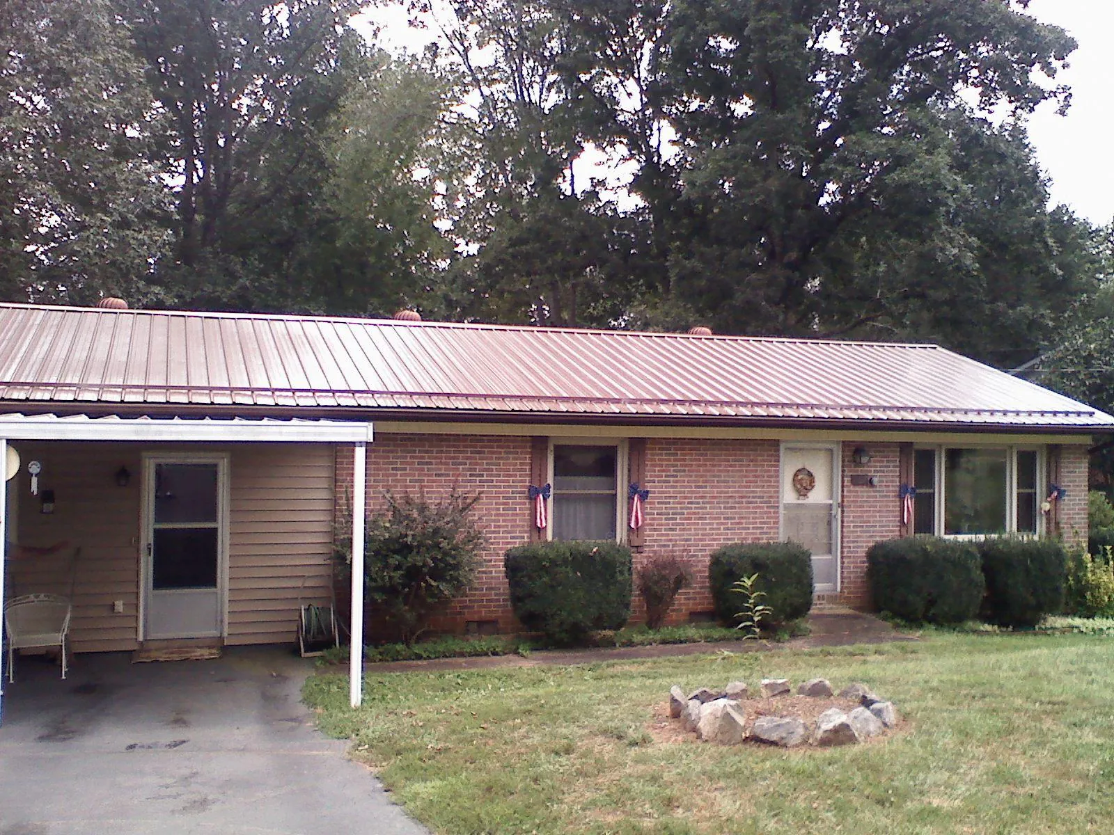 Bronze metal roof and carport on a brick ranch home — Roof Repair work by our crew in Buna